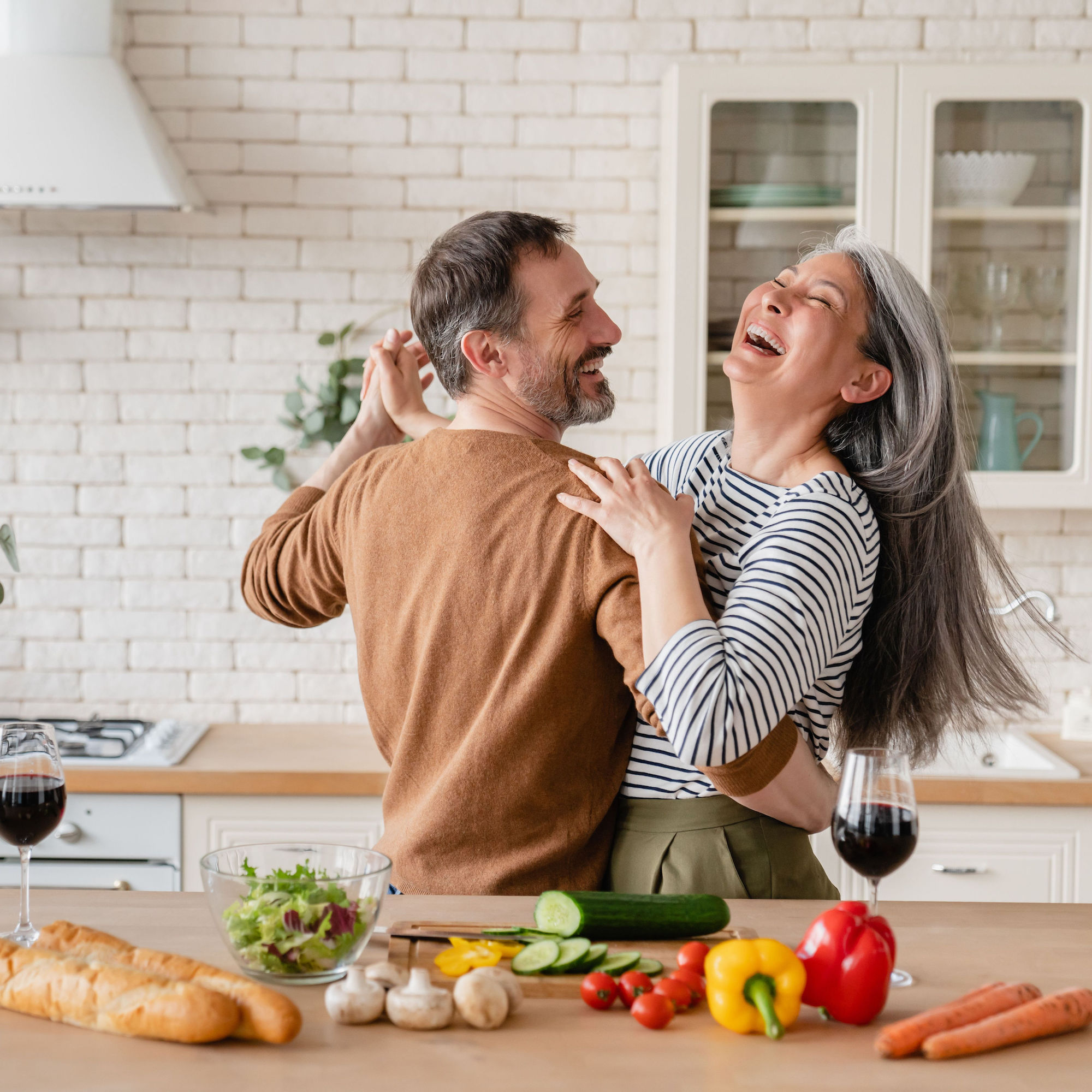 Happy couple dancing in a kitchen while making a healthy meal