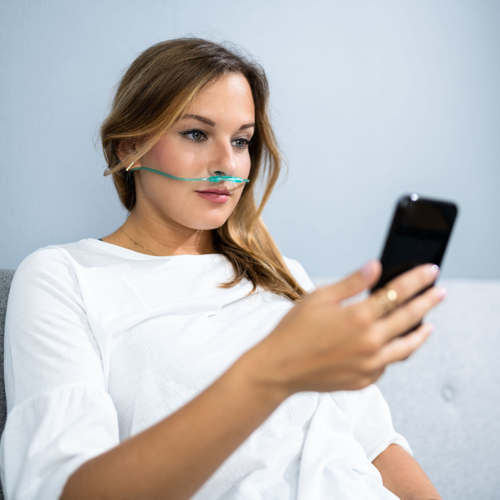 Woman inhaling hydrogen and checking out her phone