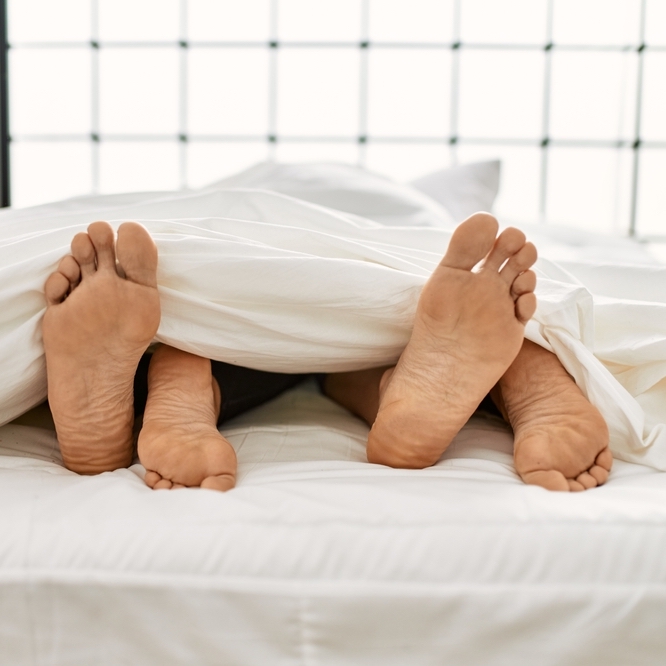 Feet of happy couple in bed post coitus