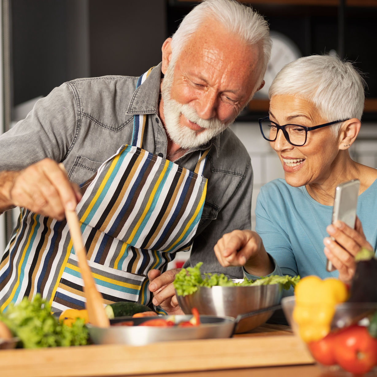 Older happy looking couple cooking a healthy meal together anti-aging, longevity optimization